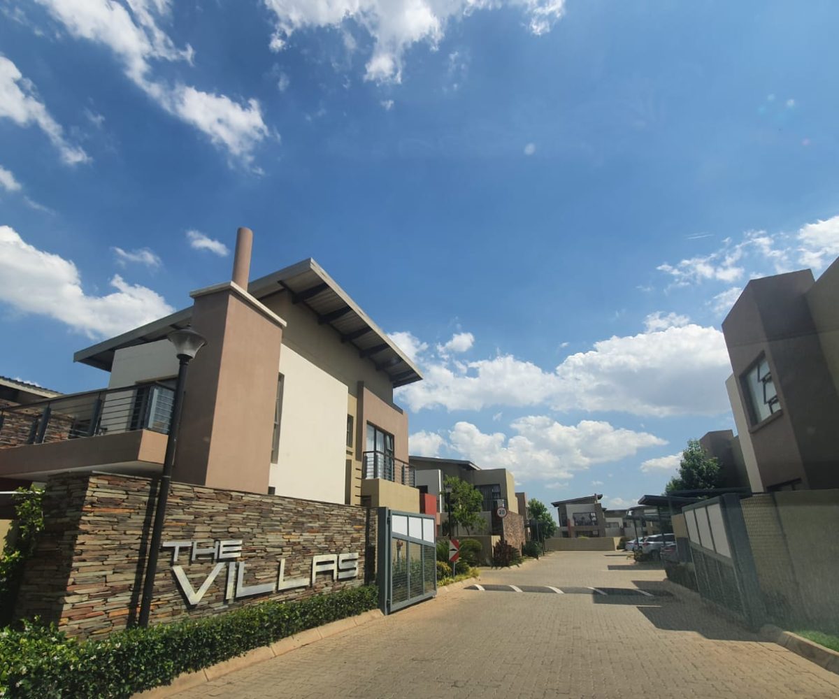 Outside view of the Villas complex gate with a townhouse that is for sale in The Villas, Glen Eagle Estate, Kempton Park. The sign that says the Villas is visible on a rock claded wall in silver letters.